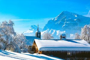 Winter mountain landscape with a building in need of snow removal. 